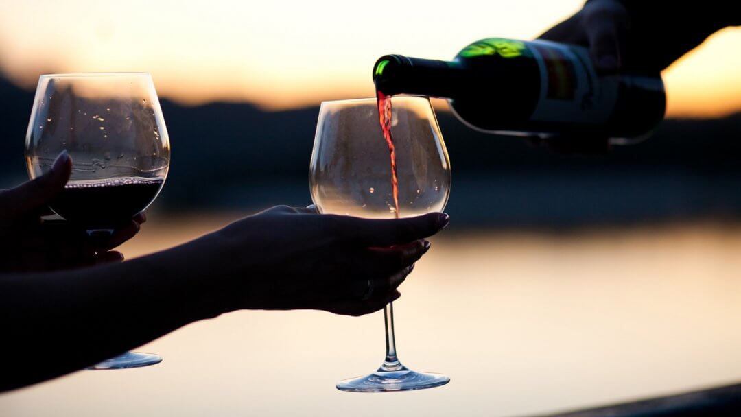 People enjoining their time with a glass of red wine during a wine tasting in sicily